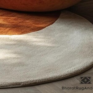 May include: A round, cream-colored rug with a half-circle of brown fur in the upper portion.