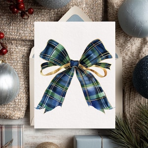 May include: A greeting card featuring a watercolor illustration of a plaid bow in shades of blue and green with gold accents. The card is on a white background, with a neutral-toned envelope and holiday decorations.