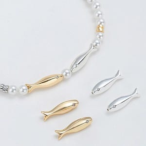 Peut inclure: Un collier de perles avec des breloques de poissons en or et en argent. Le collier a un design simple et est parfait pour tous les jours.