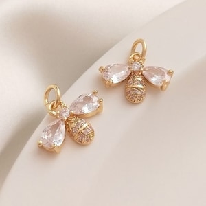May include: Two gold bee charms with clear crystal wings and a gold body. The bee charms are perfect for adding a touch of whimsy to jewelry projects.