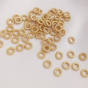 以下が含まれることがあります： ジュエリー部品を接続するために使用される小さな金属リングである、金色のジャンプリングがたくさんあります。