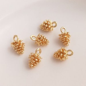May include: Six gold-toned metal pine cone charms with a loop for attaching to jewelry or crafts.
