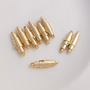 Può includere: Un set di otto chiusure magnetiche in metallo dorato per la creazione di gioielli. Le chiusure sono cilindriche e hanno una finitura liscia.