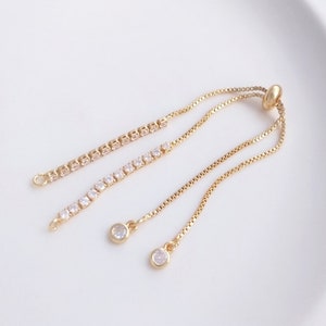 Pode incluir: Um bracelete de corrente dourada com fecho deslizante e duas filas de pedras de cristal transparentes.