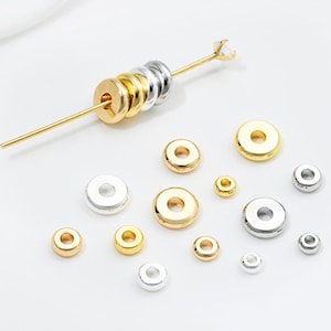 Op de afbeelding: Assortiment van gouden en zilveren springringen in verschillende maten. De springringen zijn rond en hebben een gat in het midden. Ze worden gebruikt voor het maken van sieraden.