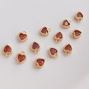 Puede incluir: Una colecci&oacute;n de 12 dijes de coraz&oacute;n dorados con acentos de cristal rojo. Los dijes tienen un dise&ntilde;o delicado y adornado y son perfectos para agregar un toque de brillo a los proyectos de joyer&iacute;a.