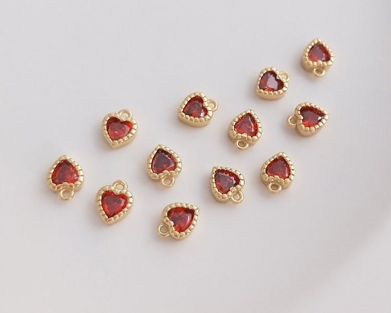 Puede incluir: Una colecci&oacute;n de 12 dijes de coraz&oacute;n dorados con acentos de cristal rojo. Los dijes tienen un dise&ntilde;o delicado y adornado y son perfectos para agregar un toque de brillo a los proyectos de joyer&iacute;a.