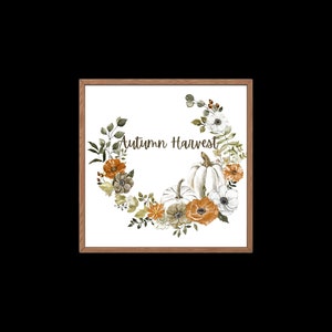 May include: A framed watercolour print depicting an autumnal wreath of pumpkins, flowers, and foliage in orange, white, and green hues. The words "Autumn Harvest" are written in the centre of the wreath.