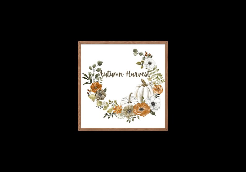 May include: A framed watercolour print depicting an autumnal wreath of pumpkins, flowers, and foliage in orange, white, and green hues. The words "Autumn Harvest" are written in the centre of the wreath.