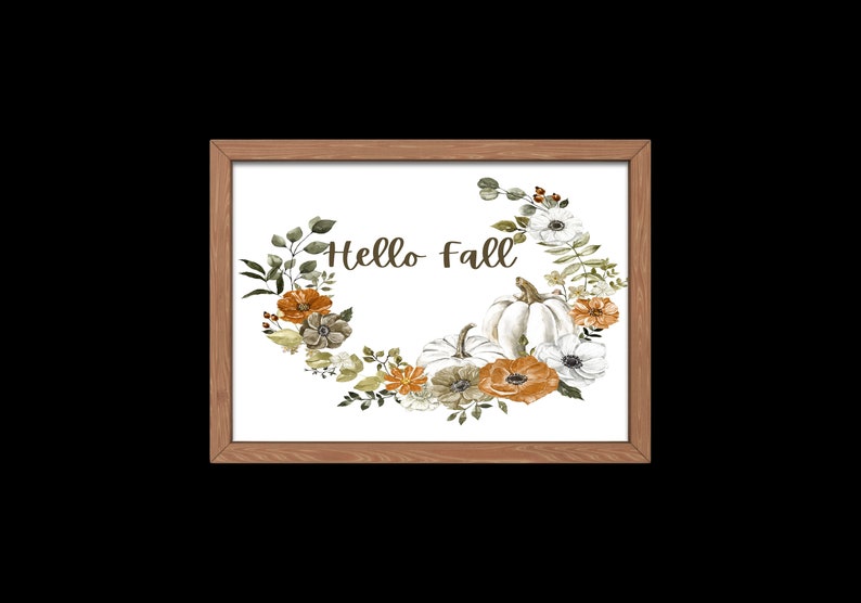 May include: A framed print with a white background featuring a watercolor illustration of a wreath of fall foliage, pumpkins, and flowers. The text "Hello Fall" is written in the center of the wreath.