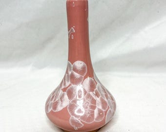 Puede incluir: Un jarrón de cerámica rosa con base bulbosa y cuello esbelto. El jarrón está adornado con un patrón blanco cristalino. Este jarrón decorativo es adecuado para exhibir flores o como pieza de arte independiente, mide unos 18 cm de alto.