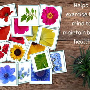 May include: A set of 13 cards featuring different flower images. The cards are white with a teal border. The text "Helps exercise the mind to maintain brain health" is written on a wooden surface.