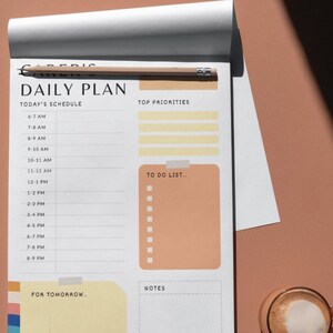 May include: A daily planner with a white background and black text. The planner has sections for today's schedule, top priorities, to do list, notes, and for tomorrow. The planner is open to a page with the time slots from 6:00 AM to 8:00 PM.