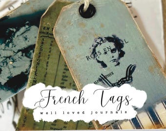 May include: Distressed vintage-style tags with a light blue and green color scheme. Each tag features faded text and imagery, including a portrait and alphabet. The tags are connected with twine and have a worn aesthetic. The text "French Tags" is visible.