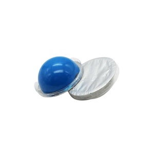 May include: Two blue, dome-shaped objects with a shiny surface, one partially uncovered, next to a silver, circular object. The objects appear to be packaged, possibly for single-use applications. The background is plain white.