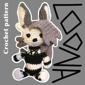 May include: A crocheted grey and white wolf plush toy wearing black and white striped clothing. The toy has a black choker with a pentagram charm. The background is grey with black text that says "ANNO".