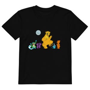 May include: Black t-shirt with a colourful cartoon graphic. The design includes a yellow bear, a frog, and other characters. The vibrant design is ideal for fans of animated shows.