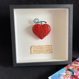 Peut inclure: Un fruit rouge en forme de cœur encadré avec une tige verte, étiqueté "Ope Ope no Mi 2008 Archipelago Sabaody".