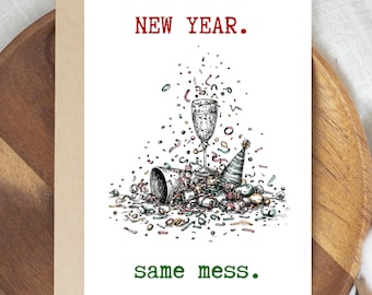 May include: A greeting card with a white background and the words "NEW YEAR." in red and "same mess." in green. The card features a black and white illustration of a champagne glass, party hats, and confetti.