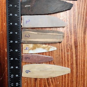 May include: A set of three ceramic mugs with a speckled, matte finish. The mugs are in shades of cream, light gray, and dark gray. Each mug has a simple, minimalist design and a rounded handle.