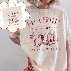 May include: Ivory-colored t-shirt and tote bag with dark red graphics. The t-shirt reads "ME? A BRIDE? SHUT UP! 2026" with a cocktail, lingerie, and crown design. The tote bag says "THE BACH DIARIES" and "KARLI'S BACHELORETTE".