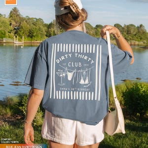 Puede incluir: Una camiseta azul vaquera con un gr&aacute;fico blanco que dice "Dirty Thirty Club" con un c&oacute;ctel, un bikini y el texto "Miami, FL". La camiseta tambi&eacute;n dice "Emma's 30th Birthday".