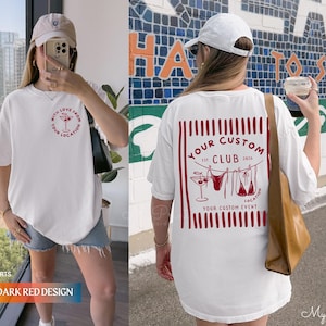 Puede incluir: Camiseta blanca con gr&aacute;ficos en rojo oscuro. La parte delantera presenta un dise&ntilde;o circular con una copa de c&oacute;ctel y texto. La parte trasera muestra un dise&ntilde;o rectangular con un c&oacute;ctel, un bikini y el texto "YOUR CUSTOM CLUB".