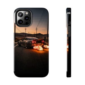 Op de afbeelding: Zwarte telefoonhoes met een grijze sportwagen op een weg bij zonsondergang, met vlammen uit de uitlaat. De hoes heeft een glanzende afwerking en een zwarte rand.
