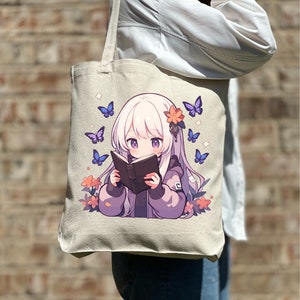 May include: A white canvas tote bag featuring a design of a young girl with long white hair reading a book. The girl is surrounded by purple flowers and blue butterflies.