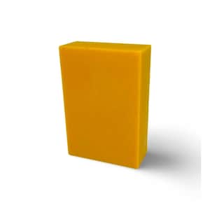 May include: A solid, rectangular block of yellow soap. The soap has a smooth surface and is slightly angled, casting a shadow on the white background. The color is a vibrant, sunny yellow.
