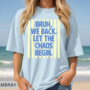 May include: Light blue t-shirt with the text "BRUH, WE BACK. LET THE CHAOS BEGIN." in blue letters on a yellow striped background. The shirt is made of a soft material and has short sleeves.