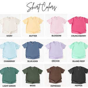 K&ouml;nnte beinhalten: Ein Raster aus zw&ouml;lf kurz&auml;rmeligen T-Shirts mit einem kleinen V-Ausschnitt-Detail, beschriftet mit dem Text Shirt Colors und den einzelnen Farbnamen: Ivory, Butter, Blossom, Crunchberry, Chambray, Bluejean, Orchid, Island Reef, Light Green, Moss, Espresso und Pepper.