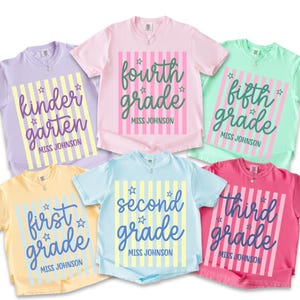 May include: Six short-sleeved t-shirts in lavender, light pink, mint green, pale yellow, light blue, and hot pink. Each shirt features a vertical striped rectangle with the text kindergarten, fourth grade, fifth grade, first grade, second grade, or third grade, plus the name Miss Johnson and small star icons.