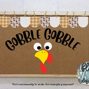 May include: A brown corkboard with a wooden frame, decorated with a Thanksgiving-themed banner. The banner has a checkered pattern and images of turkeys, pilgrims, and pumpkins. The corkboard also has a turkey face with googly eyes and the words "Gobble Gobble" written in black.