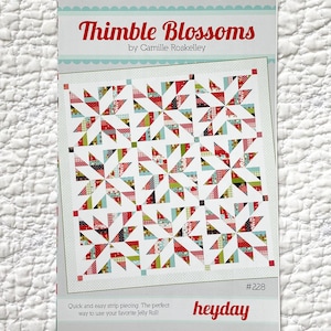 May include: A sewing pattern titled "Thimble Blossoms" by Camille Roskelley. The pattern features a quilt design with star-like patterns in red, green, and blue fabrics. The text "heyday" is also visible.