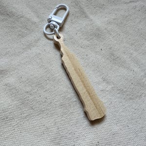 May include: A wooden keychain shaped like a bottle with a silver metal clasp.