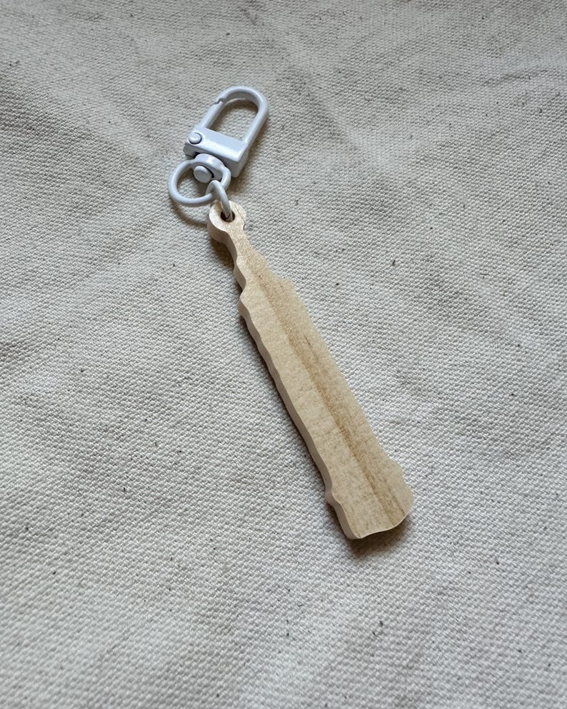 May include: A wooden keychain shaped like a bottle with a silver metal clasp.