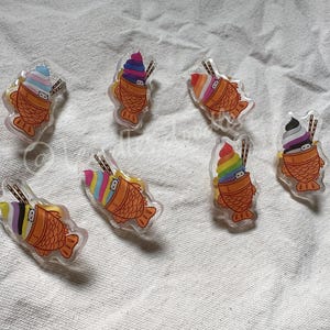 May include: Assortment of colorful ice cream cone shaped pins with a fish design. The pins are made of clear plastic with a printed design. The ice cream cones are topped with different colors of ice cream and sprinkles.