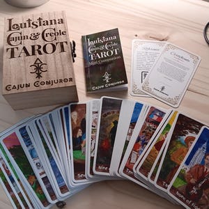 May include: A wooden box with the text "Louisiana Cajun & Creole Tarot Cajun Conjuror" on the front. The box contains a deck of tarot cards with colorful illustrations. A small booklet titled "Louisiana Cajun & Creole Tarot Mini Companion Cajun Conjuror" is also included.