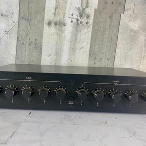 May include: Black audio/video patching system with multiple knobs and labels. The unit has the text "AUDIO/VIDEO PATCHING SYSTEM" and "AUDIO FROM" and "VIDEO FROM". The unit has a power button and the model number "VSA-5".