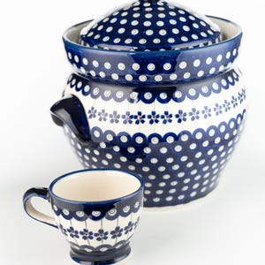 Könnte beinhalten: Eine blaue und weiße Keramik-Servierschüssel mit Deckel und eine passende Tasse. Die Schüssel und der Deckel sind mit einem Tupfenmuster verziert, während die Tasse ein Blumenmuster aufweist. Das Set ist aus Keramik.