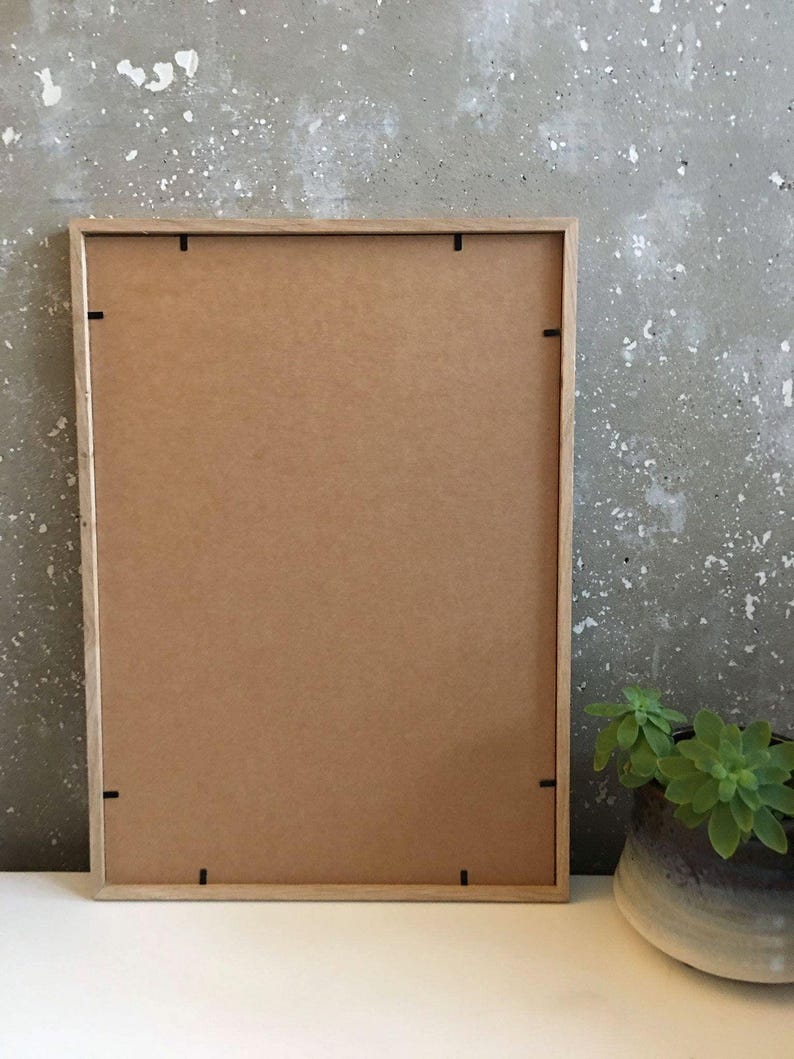 May include: A wooden picture frame with a brown cardboard backing. The frame has a simple design and is ready to display a photo or artwork.
