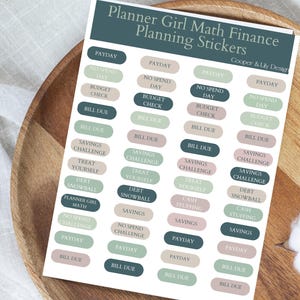 May include: A sheet of planner stickers with text including "Payday," "No Spend Day," and "Budget Check." The stickers are in various colors, including green, beige, and pink, with the text "Planner Girl Math Finance Planning Stickers."