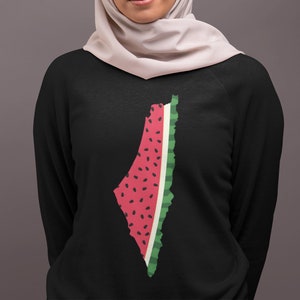 May include: A black sweatshirt with a watermelon design in the shape of Israel. The watermelon is red with black seeds and green rind.