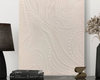 May include: A white canvas painting with a textured, raised design of white circles and lines. The background is a light beige colour.