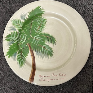 May include: A white ceramic plate with a green painted Mexican Fan Palm tree. The plate has the text "Mexican Fan Palm (Washingtonia robusta)" written on it.