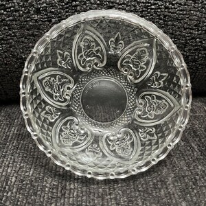 May include: A clear glass bowl with a decorative pattern of hearts and flowers. The bowl has a beaded edge and a diamond-shaped pattern on the bottom.