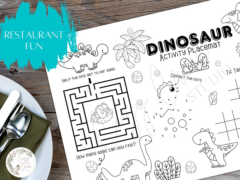 May include: A white dinosaur activity placemat with black line art illustrations. The placemat features a maze, connect-the-dots, and tic-tac-toe, with the text "DINOSAUR ACTIVITY PLACEMAT" and "RESTAURANT FUN".