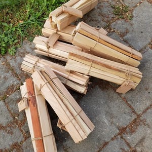 May include: Bundles of natural wood slats tied together with twine. The slats are approximately 12 inches long and 1 inch wide.