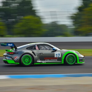May include: A green and grey racing car with the number 17 on the side. The car is on a race track and is moving at high speed. The car has the words "Advanced Collision" on the side.